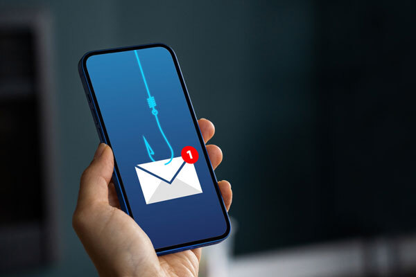 Image of a cell phone in a hand with an email showing a phishing hook on the screen.